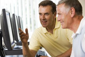 men smiling while looking at computers