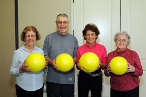 four adults holding yellow balls