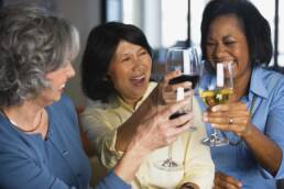 smiling women toasting with wine